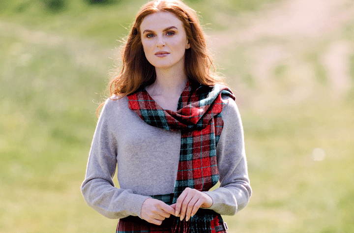 Mujer con pelo largo rojo y jersey gris que lleva una bufanda de lana cepillada en tartán Thompson Red Modern y falda a juego.